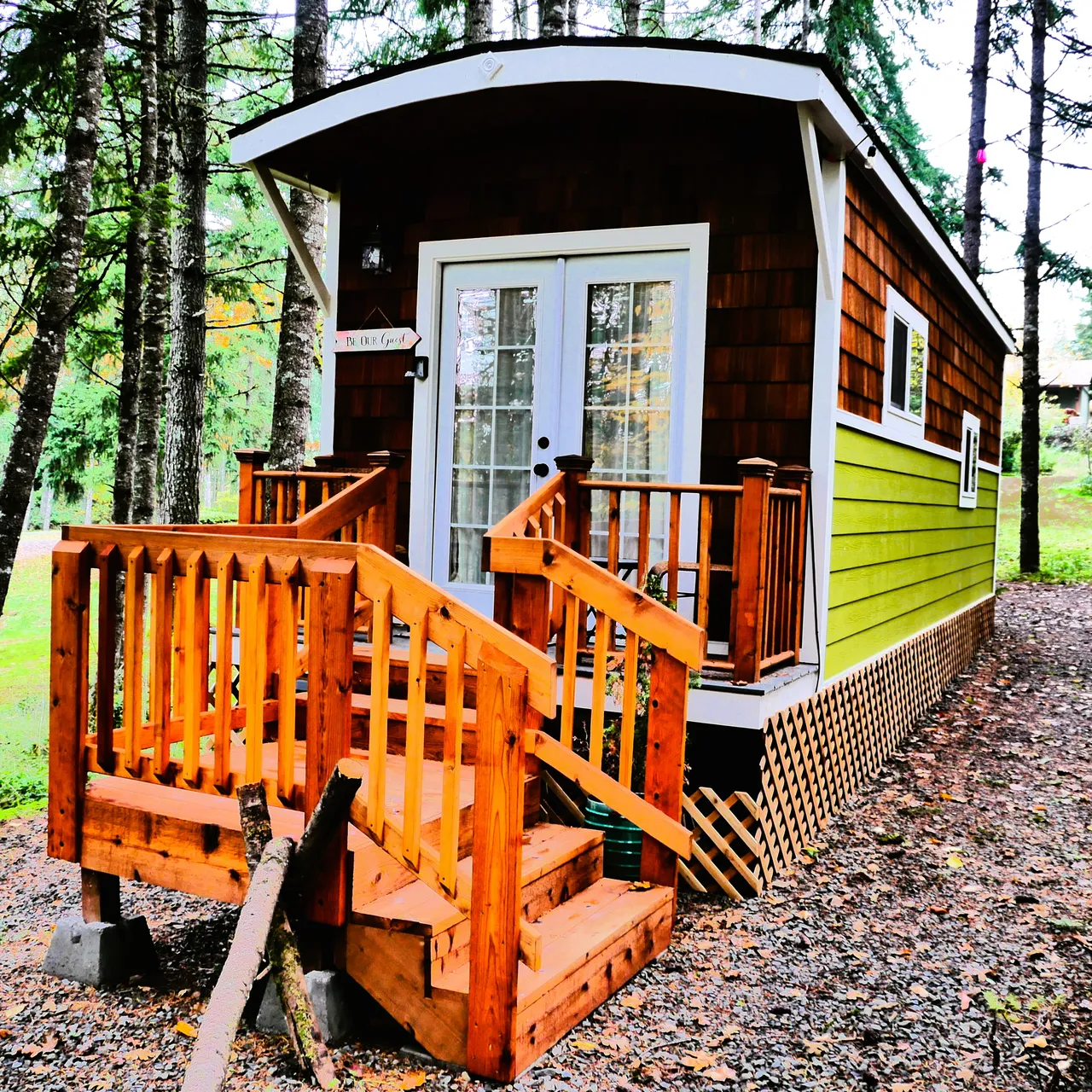 Small wooden tiny home with a porch among trees